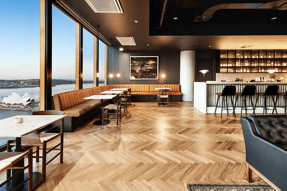 A beautiful Sydney apartment with views of the opera house in the distance, and a bar set-up in the middle of the room