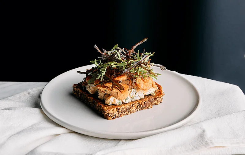 A fancy food dish seving on a white plate, with a black backdrop