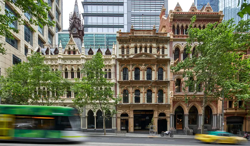 Historic, ornate Victorian facades stand along a street framed by leafy trees and modern skyscrapers, as a green tram blurs past in the foreground. Text reads: "RECORD CHAMBERS" and "OLDERFLEET".