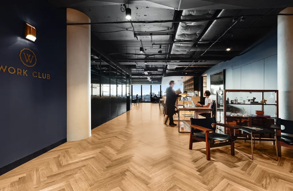 Work Club lounge with navy walls, herringbone timber floors and members seated at tables