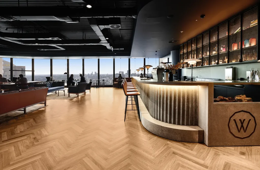 Curved timber bar with the Work Club logo, herringbone timber floors and city views
